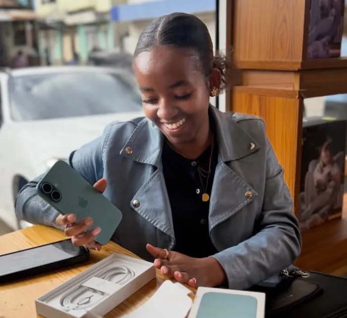 A young woman unboxing a new phone at a table