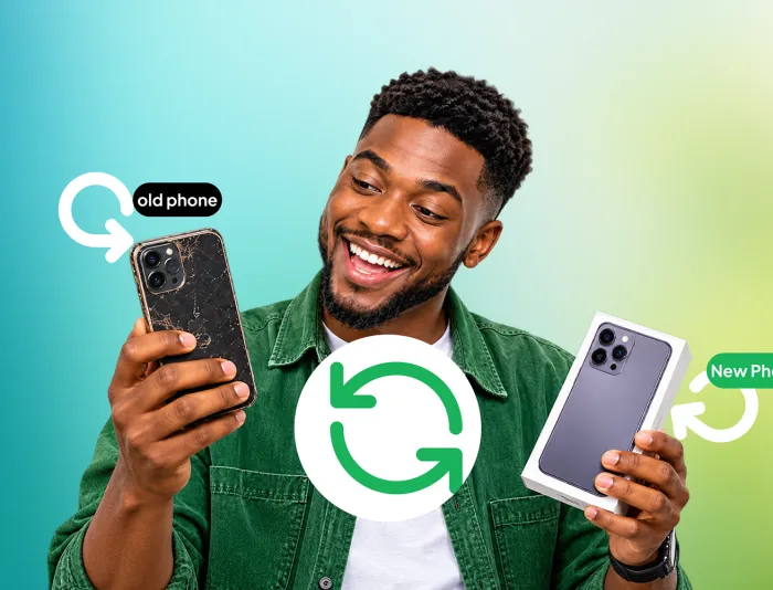 A smiling man holding his old phone in one hand and a new phone in the other